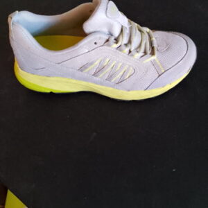White and yellow athletic shoe on a dark surface.