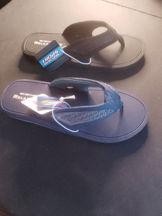 A pair of blue and black flip-flops on a dark surface.